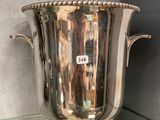 a silver vase sitting on a glass shelf in a room