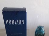 un vase en verre bleu posé sur une table à côté d'un coffret de parfum « Horizon »