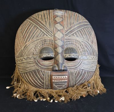 an image of a wooden mask with fringes on a black background