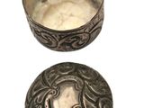two silver bowls with designs on them on a white surface