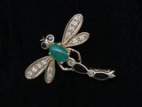 une photo d'une broche en forme de libellule dont les ailes sont ornées de diamants