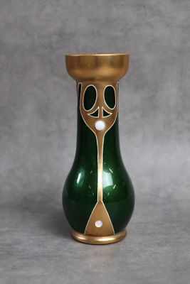 un vase vert et doré posé sur une surface grise