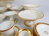 beaucoup d'assiettes et de bols blancs et dorés sur la table