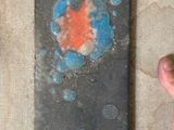 une petite œuvre d'art posée sur une table, avec la main d'une personne