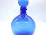a blue glass bottle sitting on a white surface