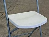 a white folding chair sitting in a garage