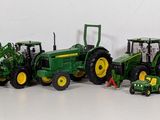 many toy tractors lined up in a row on a white surface
