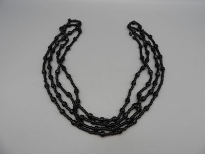 un gros plan d'un collier noir posé sur une surface blanche
