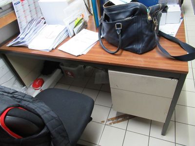 un sac à main noir posé sur un bureau en bois, à côté d'une chaise noire