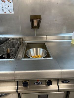 plan de travail en acier inoxydable dans une cuisine professionnelle équipée d'une friteuse et d'un évier