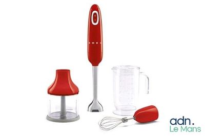un mixeur rouge posé à côté d'un mixeur et d'un verre doseur