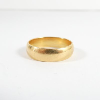 gros plan d'une bague en or sur une surface blanche
