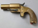 a close up of a brass revolver on a white surface