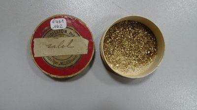 une petite boîte de paillettes dorées à côté d'une petite boîte de paillettes dorées