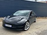 une Tesla Model S noire garée devant un mur bleu