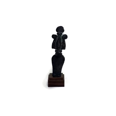une statue représentant un homme tenant un bébé dans ses bras, posée sur un socle en bois