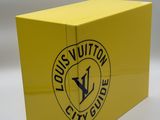a close up of a yellow box with the louis vuitton city guide logo on it