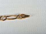 the gold chain has been placed on top of a white surface