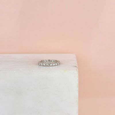 un gros plan d'une bague en diamant posée sur un bloc de marbre blanc