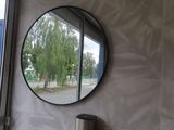 a round mirror on the wall above a sink in a bathroom