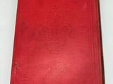 an old red book sitting on top of a white table