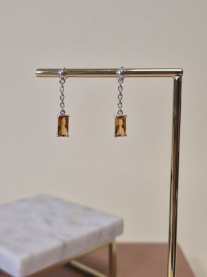 des boucles d'oreilles posées sur un présentoir en or, avec un banc en marbre en arrière-plan