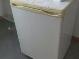a small white refrigerator in the corner of a room
