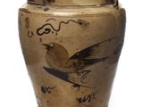 un vase marron orné d'un oiseau sur un fond blanc