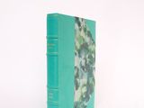 a green book that is sitting on a white surface
