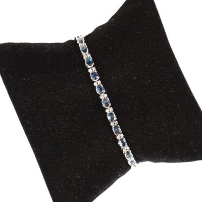 un gros plan d'un bracelet posé sur un oreiller, sur fond blanc