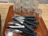 a tray with knives and glasses on it on a table