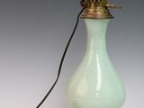 une lampe en verre vert clair munie d'un support métallique