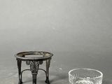 a small table with a glass on it next to a small bowl