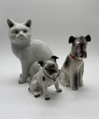 three figurines of dogs and a cat on a white background
