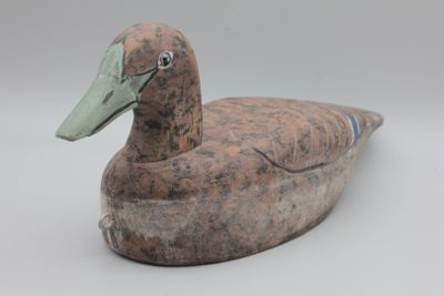 un petit canard en bois posé sur une table