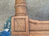 a close up of a wooden chair with a person standing next to it