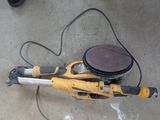 a yellow and black machine on the ground with a sander