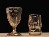 two wine glasses sitting on a table with a black background