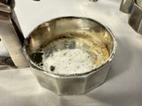 a small metal cup with a handle on a table