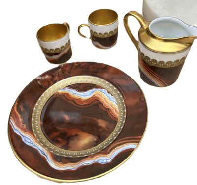 a plate, cups, and a pitcher on a table