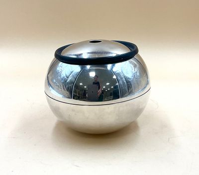 une boule argentée munie d'un manche noir, posée sur une table