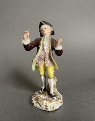 figurine représentant un homme coiffé d'un chapeau et vêtu d'un pantalon jaune, les mains levées