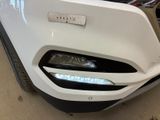 the front bumper of a white car with a number plate on it