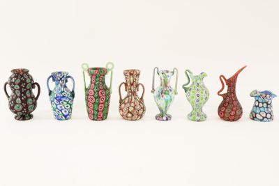 several different colored vases are lined up on a white surface
