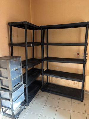 une étagère noire dans un coin de la pièce, à côté d'une pile de boîtes en plastique