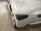 a white car that has been dented and is parked in a garage