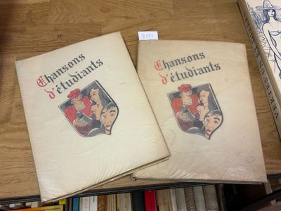 deux livres posés sur une table en bois, à côté d'une pile de livres