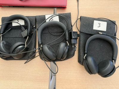 several headphones are lined up on a table next to a laptop