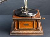a small antique record player sitting on top of a wooden stand