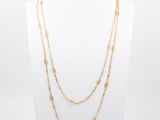 un collier à chaîne en or composé de trois rangées de perles en or différentes